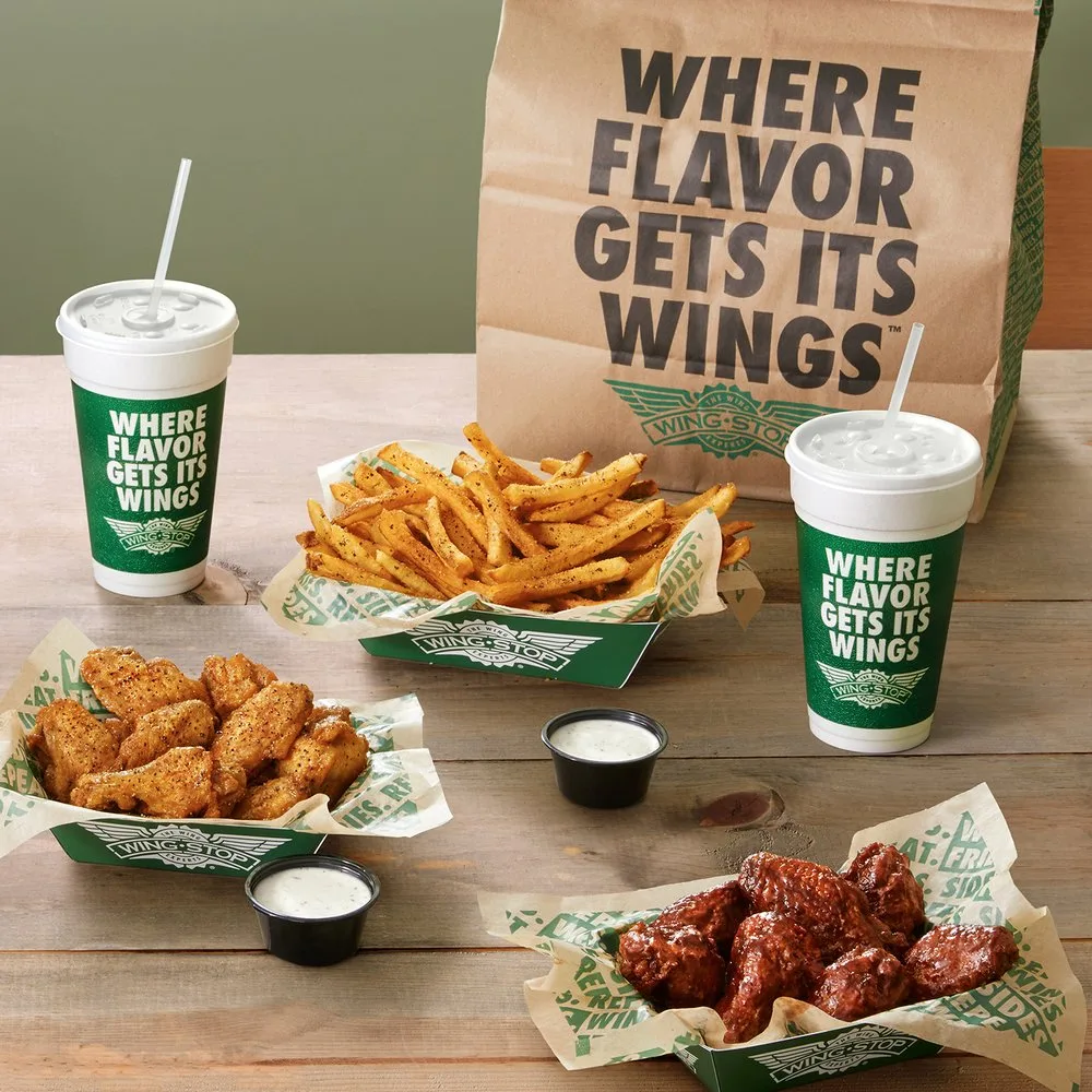 Wingstop takeout meal with wings, fries, drinks, and branded packaging